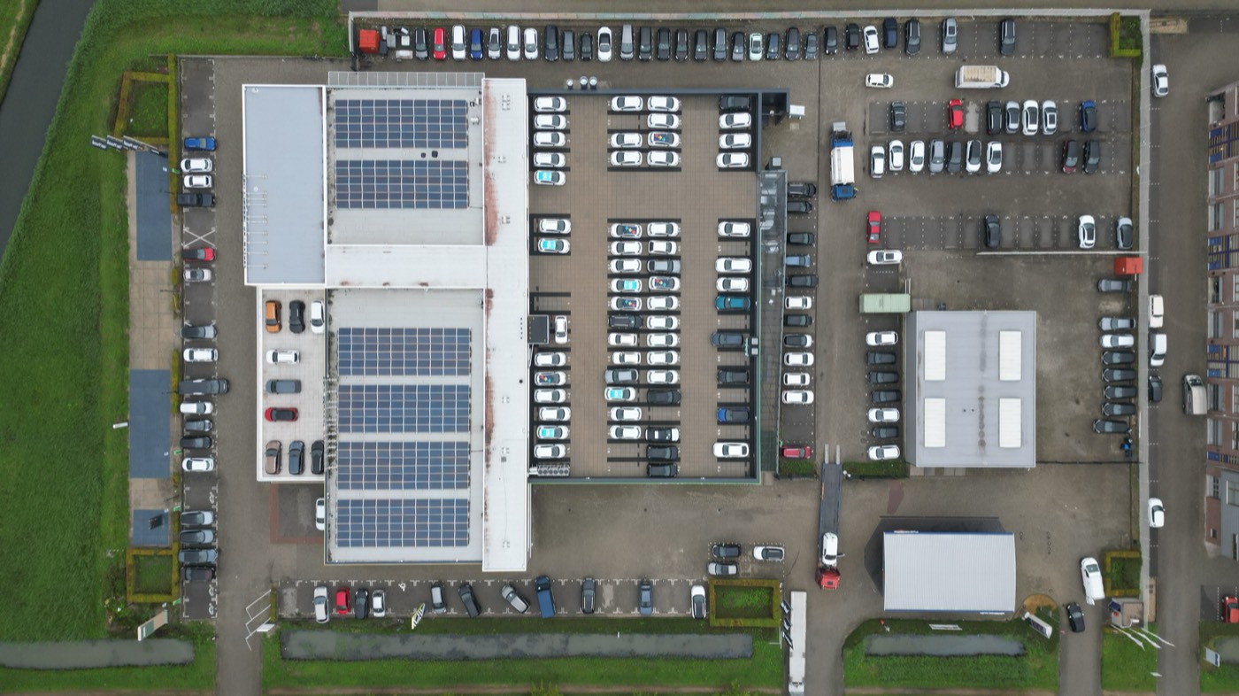 A warehouse roof with a solar array and its car park, from directly above