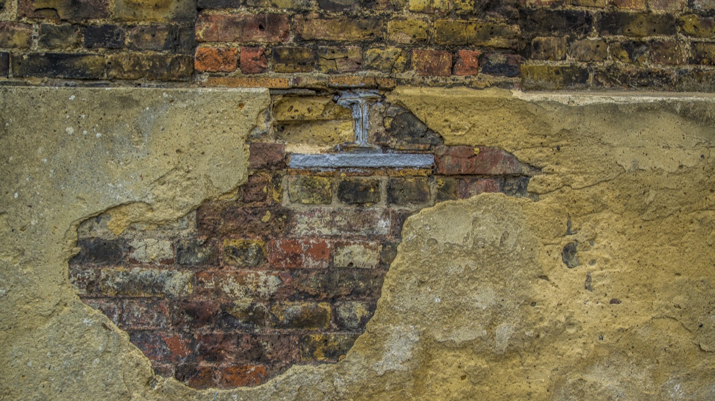 An old brick wall with a worn render patch and exposed brickwork