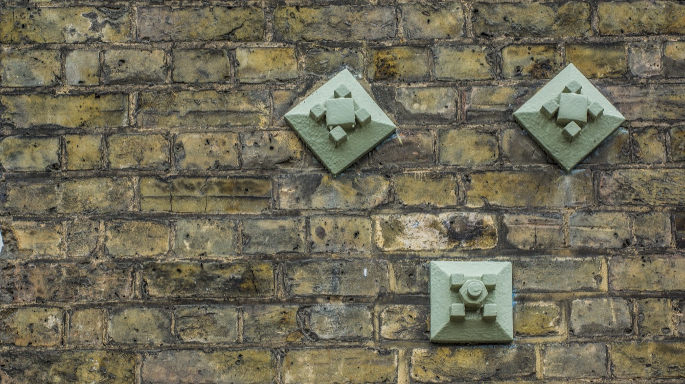 Diamond-shaped pattress plates restraining an old brick wall