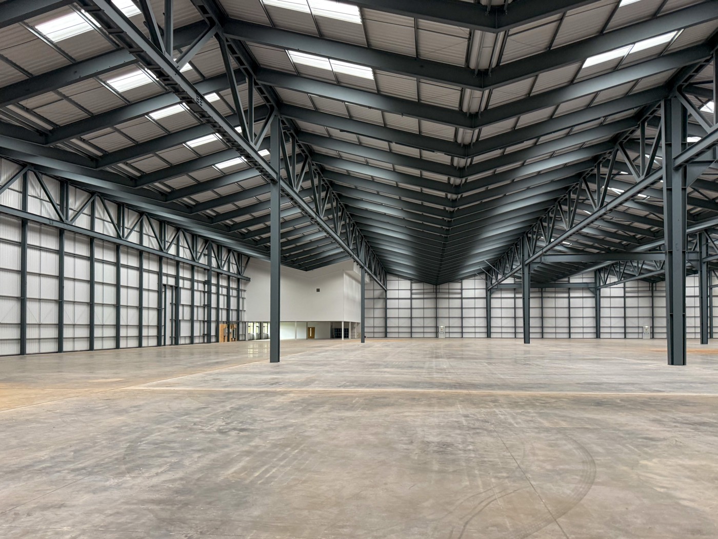 Inside a large new warehouse: steel portal frames, roof lights and a concrete floor